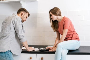 Genç yetişkin karı koca sabahlarını mutfakta geçiriyorlar.