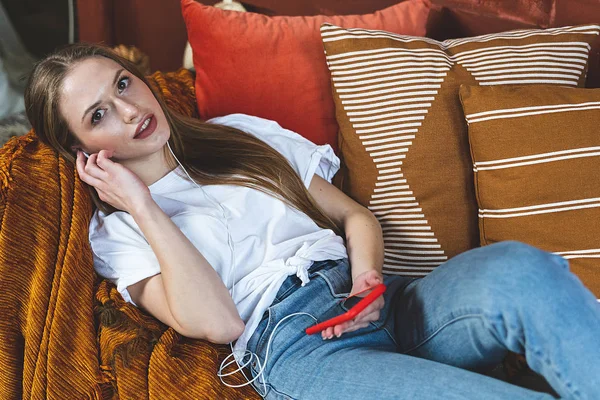 Jovem mulher adulta descansando em casa com smartphone nas mãos — Fotografia de Stock