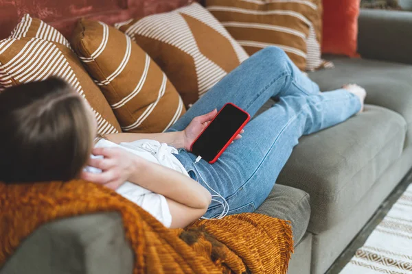 Mujer joven adulta descansando en casa con smartphone en las manos — Foto de Stock