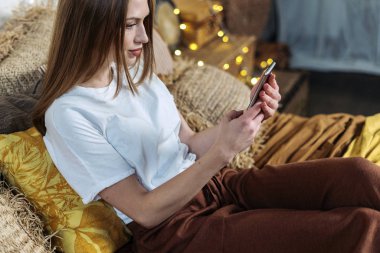 Genç yetişkin bir kadın rahat yatak odasında dinleniyor.