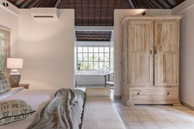 Yatak odası, dolap, klima, duvarda fotokopi odası ve zarif bir dairenin banyo penceresi olan beyaz bir iç mekan.