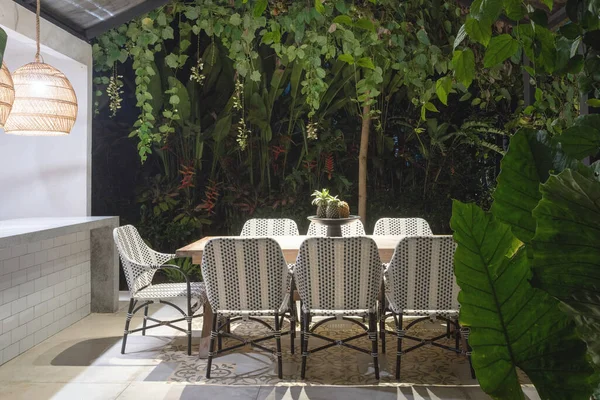 Akşam yemek masası ve rahat sandalyeler yeşil doğal arka plana karşı açık mutfakta.