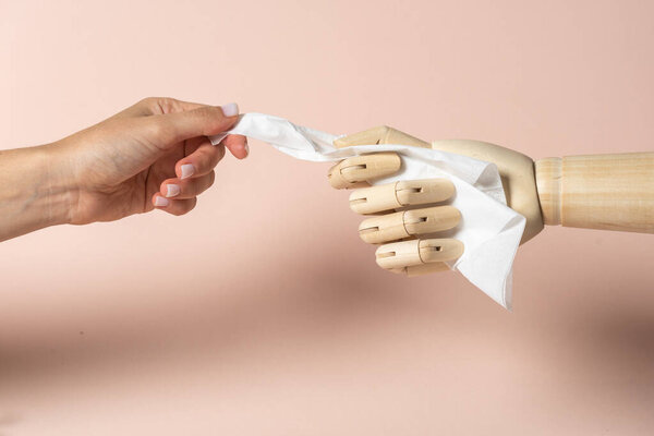 Illness and allergy disease concept. Cropped view of sick young adult woman take white napkin from wooden mannequin hand isolated on pastel pink background with copy space
