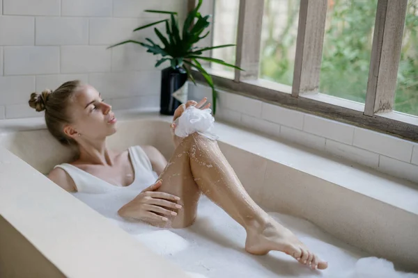 낙천적 목욕을 스펀지를 다리를 아침을 화장실에서 보낸다 — 스톡 사진