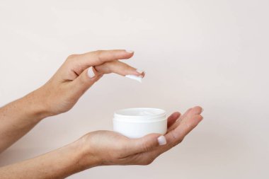 Elinde vücut bakımı ve cilt kremi olan genç bir kızın görüntüsü. Organik kozmetik ürünü kopyalama alanı olan beyaz arkaplanda izole edildi