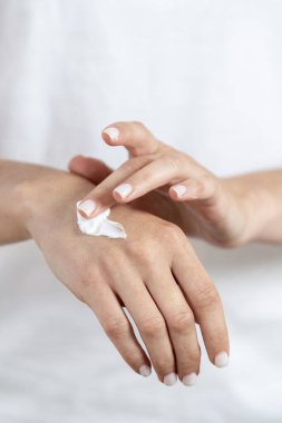 Yaşlanma karşıtı doğal ve organik kozmetik ürünler. Genç yetişkin bir kızın cildine krem sürerken kesilip dikey görünümü
