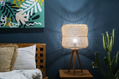 Yatak odası, modern iç dekorasyon, komodinin üzerinde lamba, rahat yatak, duvarda kaktüs bitkisi ve sanat eserleri. Konforlu evde oda kavramı