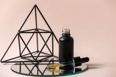 Organik kozmetik ürünü kavramı. Pipetli cam şişe ve pastel pembe arka planda izole edilmiş yaşlanmayı önleyici serumun formülü.