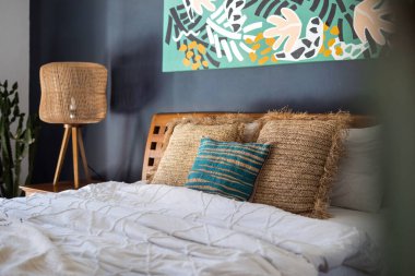 Geleneksel Asya iç yatak odası, yatak yastıkları tablonun altında, kaktüs bitkisinin yanında ve komodinin üzerinde. Etnik dekorlu rahat ev kavramı