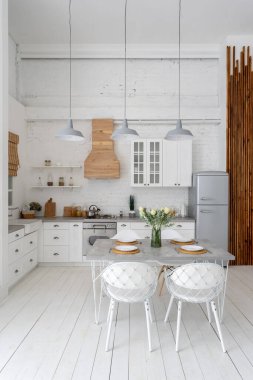 Mobilyalı, yemek masalı, gaz ocaklı, buzdolabı, fırın, ahşap dolaplı ve tezgahlı modern evin mutfağının dikey fotoğrafı.