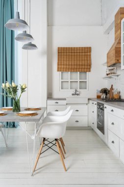 Modern iç mekan stili, yemek masası dekorasyonu, gaz ocağı, buzdolabı, fırın, ahşap dolaplar mobilya ve pencerenin yanındaki lavabonun dikey fotoğrafı.