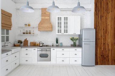 Modern mutfağın önü beyaz iç mekan, yeni mobilya, gaz sobası, fırın, buzdolabı, ahşap dolaplar, tezgah, pencerenin yanına lavabo ve ahşap zemindeki boşluğu kopyalayarak.