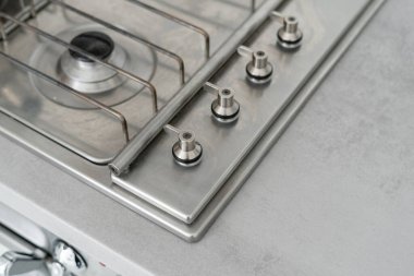 Regülatör saplı yeni metalik gaz sobasının yüksek açılı görüntüsü. Modern iç mimari tarzına sahip çağdaş mutfak ve tezgahın üstündeki alanı kopyala