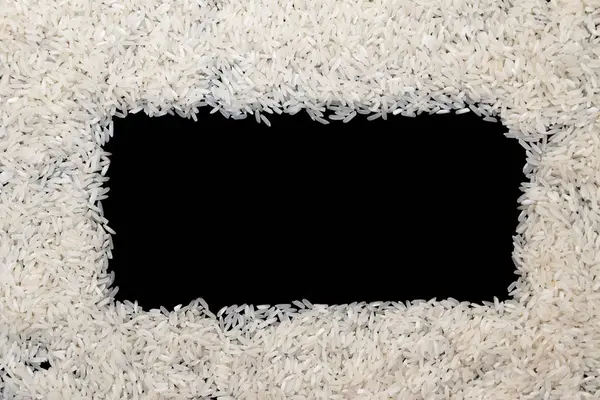 Arroz branco espalhado sobre fundo preto. Espaço de cópia para texto em — Fotografia de Stock