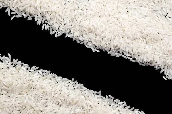 Белый необработанный рис, разбросанный на черном фоне. Копировальное пространство — стоковое фото