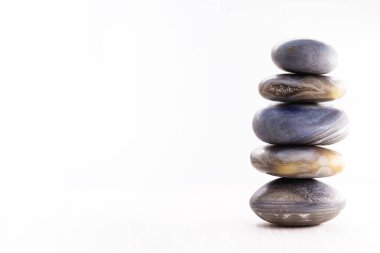 Masanın üzerine beyaz bir arkaplan ile spa taşı yığını, yazı için boşluk. Meditasyon ve mistik şifa için Zen taşları.