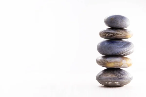 Pilha de pedras spa sobre a mesa contra um fundo branco, espaço para texto. Pedras Zen para meditação e cura mística . — Fotografia de Stock