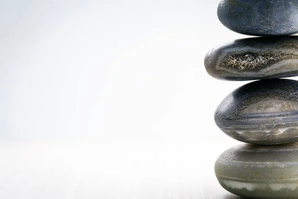 Stapel von Wellness-Steinen auf dem Tisch vor weißem Hintergrund, Platz für Text. Zen-Steine für Meditation und mystische Heilung. — Stockfoto