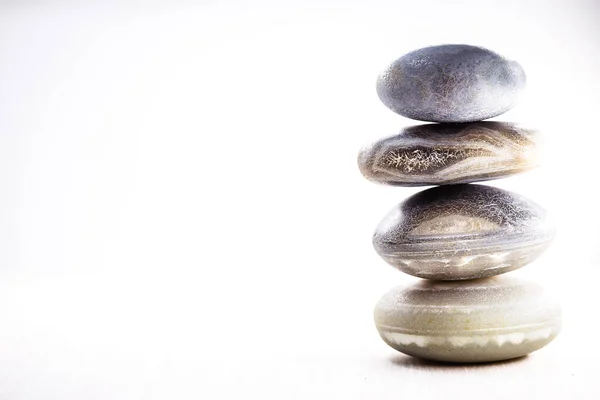 Mucchio di pietre termali sul tavolo su sfondo bianco, spazio per il testo. Pietre zen per la meditazione e la guarigione mistica . — Foto Stock