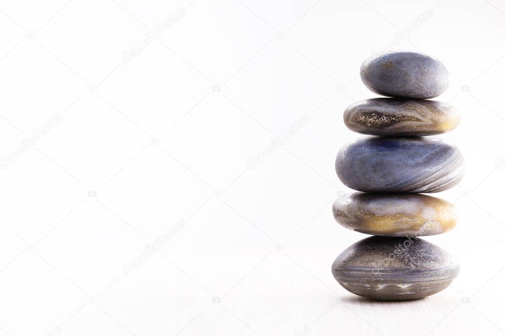 Pile of spa stones on the table against a white background, space for text. Zen stones for meditation and mystical healing.