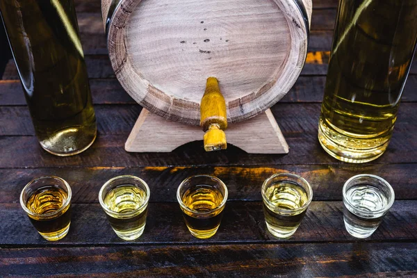 Hand holding glass of alcoholic drinks, cachaça, drips, rum and cognac. Selection of strong and hard alcoholic drinks, glasses. Vodka, cognac, whiskey, grappa, liqueur, vermouth, tincture, rum. — Stockfoto