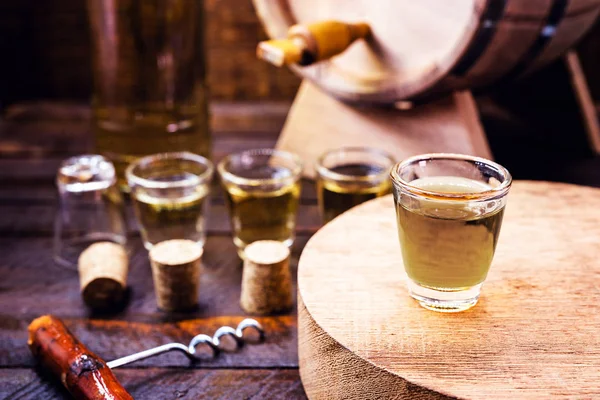 Glass of golden rum, with bottle. Bottle pouring alcohol into a small glass. Brazilian export type drink. Brazilian product for export, distilled drink known as brandy or pinga. Day of cachaça. — 스톡 사진