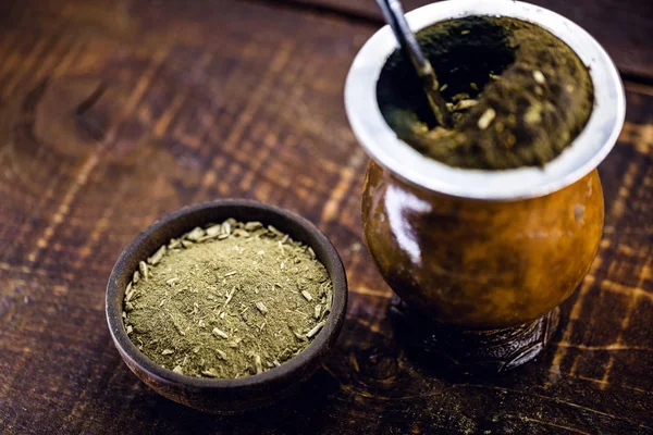 Chimarrão, or mate herb, is a South American drink left by indigenous cultures. It consists of a gourd, a pump, ground yerba mate and boiling water. Chimarrão isolated on wooden background. Copy space —  Fotos de Stock