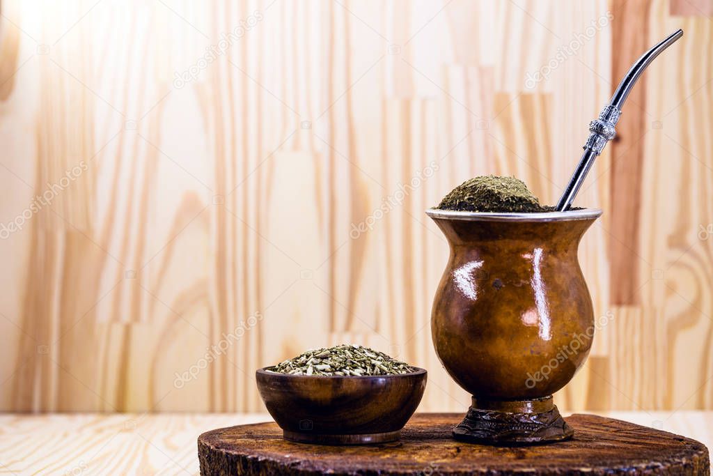 Traditional Argentinian, Brazilian and Uruguayan yerba tea in a gourd gourd with bombilla stick against wooden background