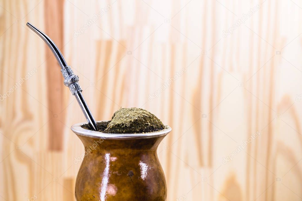 Traditional Argentinian, Brazilian and Uruguayan yerba tea in a gourd gourd with bombilla stick against wooden background