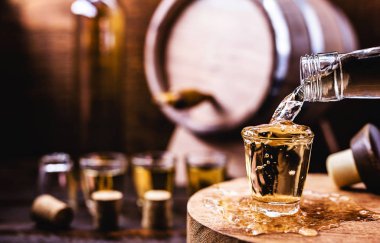 Glass of golden rum, with bottle. Bottle pouring alcohol into a small glass. Brazilian export type drink. Brazilian product for export, distilled drink known as brandy or pinga. Day of cachaça.