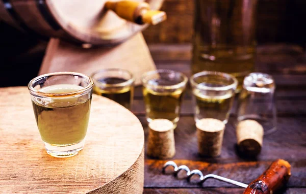 Glass of golden rum, with bottle. Bottle pouring alcohol into a small glass. Brazilian export type drink. Brazilian product for export, distilled drink known as brandy or pinga. Day of cachaça. — Stockfoto