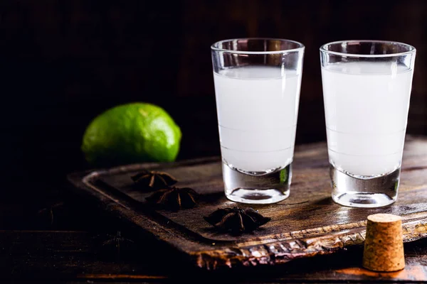 Ouzo or Uzo, is a Greek anise brandy, traditional strong alcoholic drink in glasses on the old wooden table. Greek tradition, drink of the gods. Place for text