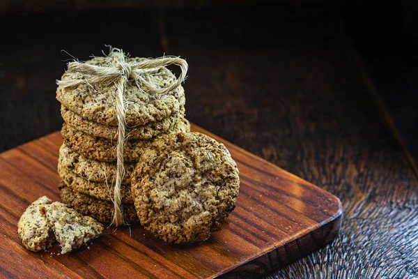 Tahıllı tam tahıllı kurabiye, kurutulmuş meyve ve eski ahşap masada çikolata.