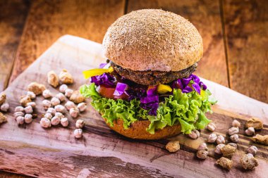 Ahşap zemin üzerinde çiğ soya ve nohut büyük vejetaryen hamburger. Vejetaryen yemeği ve sağlıklı yaşam konsepti.