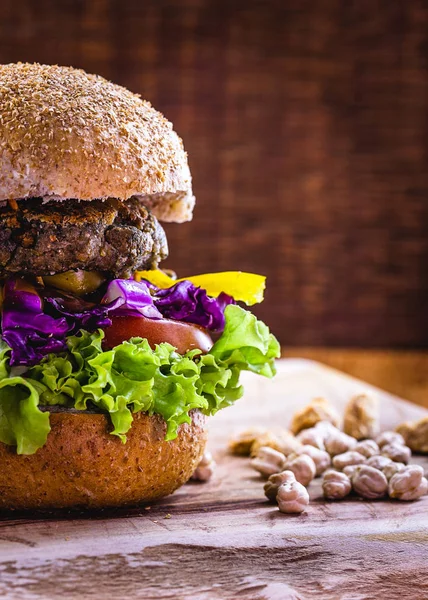 big vegan hamburger from raw soy and chickpeas on wooden background. Vegetarian food and healthy life concept.