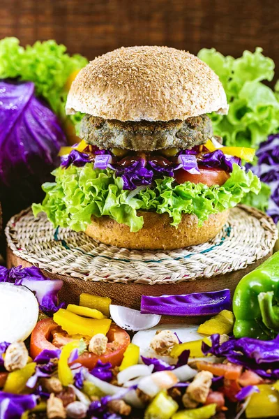 large roasted vegan hamburger, made from chickpeas and soy with proteins. Healthy and vegetarian life concept. Colorful food, peppers, red cabbage, tomatoes, onions, chickpeas, soy, lettuce and lye