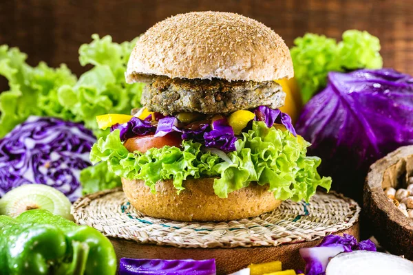 large roasted vegan hamburger, made from chickpeas and soy with proteins. Healthy and vegetarian life concept. Colorful food, peppers, red cabbage, tomatoes, onions, chickpeas, soy, lettuce and lye