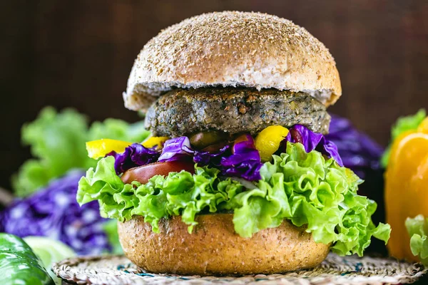 Healthy homemade vegetarian quinoa burger with lettuce and vegetarian tomatoes, peppers, bleach, chickpeas, soy, protein, and red cabbage. Meatless food concept.