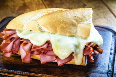 Mortadella ve erimiş peynirli ekmek. Rustik ahşap arka plan, Sao Paulo yemeği, So Paulo pazarından ünlü ekmek ve mortadella..