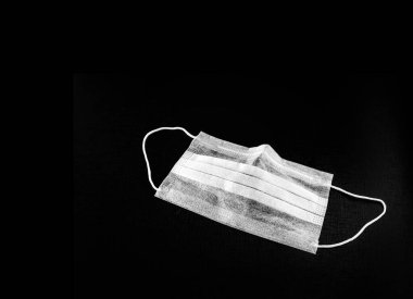 Lastik bantlı çift kullanımlık maske. Koronavirüs gibi salgın salgınları için kullanılır. Siyah arka planda izole edilmiş, salgın ve kirlenme kavramı.