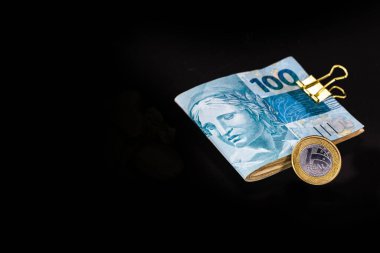 100 reais banknot ve bir reais sikke, izole edilmiş siyah arka planda Brezilya parası. Brezilya değeri, ödül veya ekonomi konsepti.