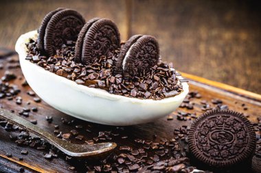 Brezilya 'dan tipik beyaz çikolata yumurtası, beyaz çikolata dolgulu ve kremalı siyah, oreo kraker ve siyah serpiştirilmiş. Paskalya 2020, kırsal ahşap zemin