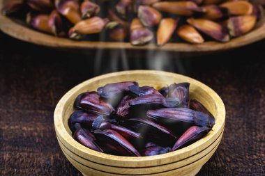 Kabukla pişirilmiş çam fıstığı. Köy tahtasında çam fıstığı tohumu. Brezilya mutfağı, kışın ve haziran partilerinde tüketilir.