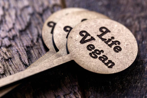 small wooden sign with inscription: Vegan life, with rustic wooden background. Concept of: Healthy and vegan food.