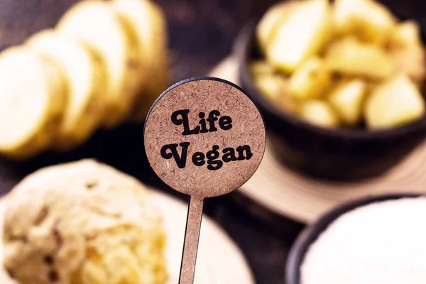 small wooden sign with inscription: Vegan life, with rustic wooden background. Concept of: Healthy and vegan food.