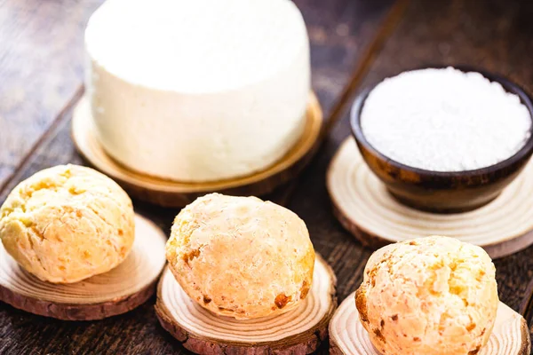 homemade Brazilian cheese bread basket, rustic wood background. Fresh cheese and flour in the background, ingredients for making cheese bread.