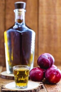 Bir bardak erik likörü, meyve bazlı alkolden yapılmış içecek. Kırsal ahşap arka plan.