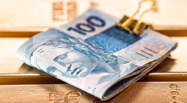 Altın külçeli Brezilya parası. 100 reais banknot, altın arka plan. Yatırım ya da zenginlik konsepti, büyük ödül.
