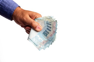 Brezilya 'dan gelen 100 reais banknotun el ele tutuşması, izole edilmiş beyaz arka planda. Maaş kavramı, talep üzerine nakit ödenen fatura..