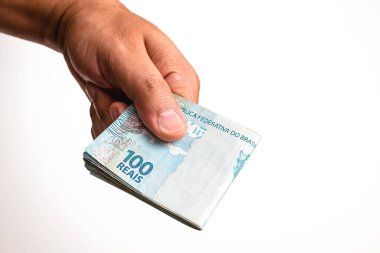 Brezilya 'dan gelen 100 reais banknotun el ele tutuşması, izole edilmiş beyaz arka planda. Ödeme veya kredi kavramı.